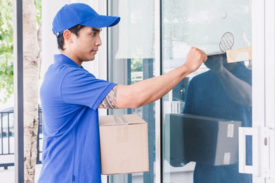 Salesman knocking door while standing with cardboard box