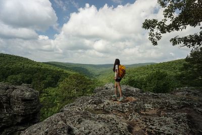 Side view of woman standing on mountain against cloudy sky