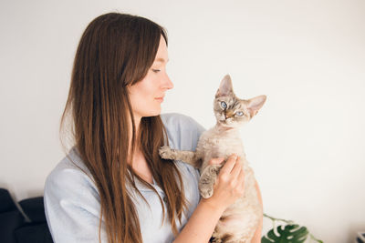 Young woman with cat against white background