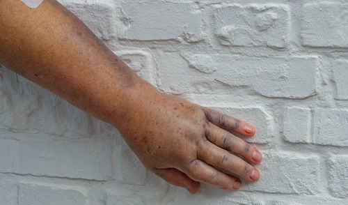 Cropped hand of person gesturing against wall