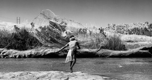 Full length of man standing on rock against sky