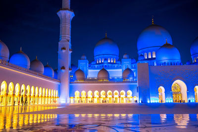 Illuminated building against blue sky at night