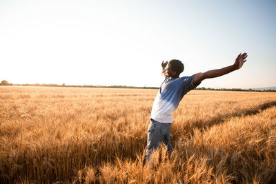 Rear view of man standing on grassy field against clear sky