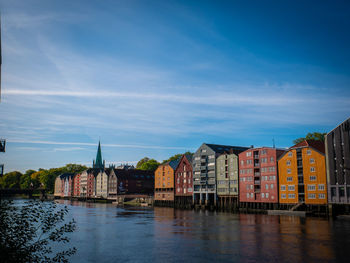 Buildings by river against sky