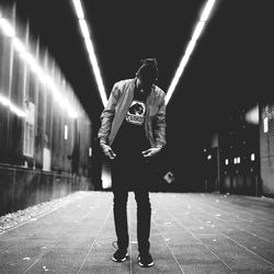 Full length of man standing at illuminated railroad station at night