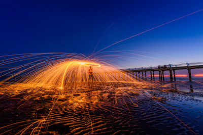 Illuminated bridge against blue sky at night