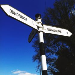 Low angle view of road sign against blue sky