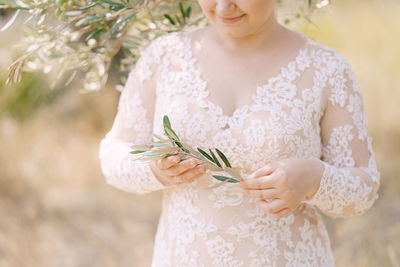 Midsection of bride holding leaves outdoors