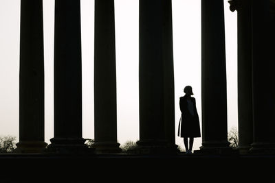 Rear view of silhouette man standing against building