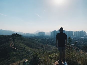 Rear view of man looking at cityscape against sky