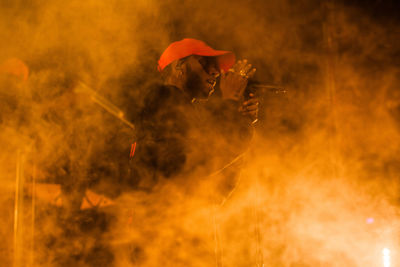 Midsection of man holding fire at night