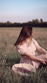 Woman sitting on field against sky