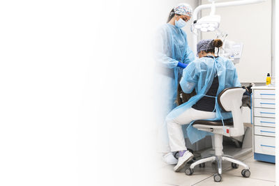 Dentist and assistant in operating gowns working at clinic