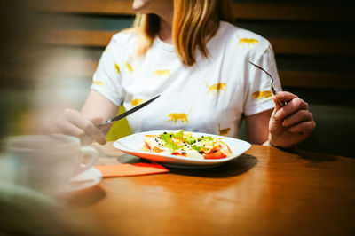 Midsection of woman having food on table
