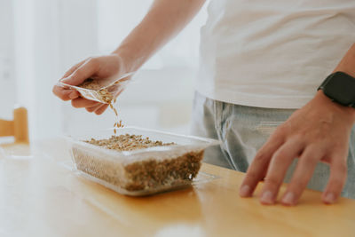 A young man plants wheat seeds in a container.