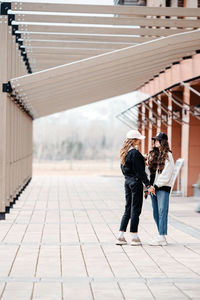 Two teenager girls walk and hold hands. casual clothing. street photography