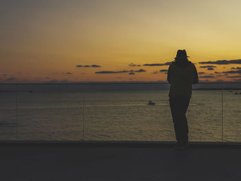 Silhouette man standing on beach against sky during sunset