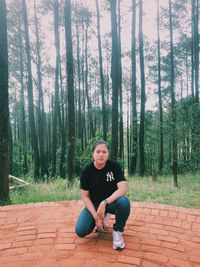 Portrait of woman sitting on land in forest