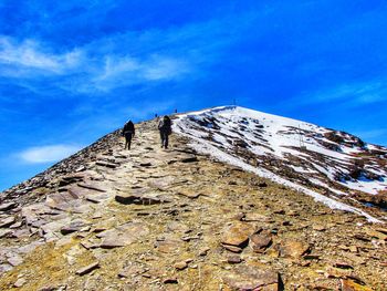 Low angle view of snowcapped mountain against blue sky