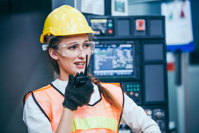 Young engineer talking on walkie talkie in factory