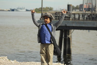 Boy with arms raised standing at beach