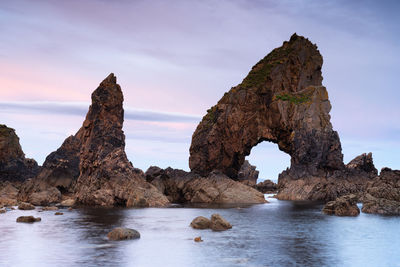 Rock formation in sea against sky