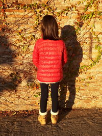 Rear view of woman standing by autumn leaves