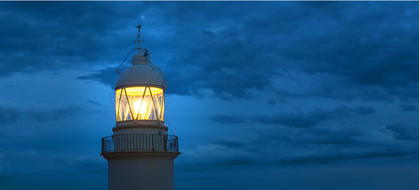 Lighthouse glowing at dark night on coast spain