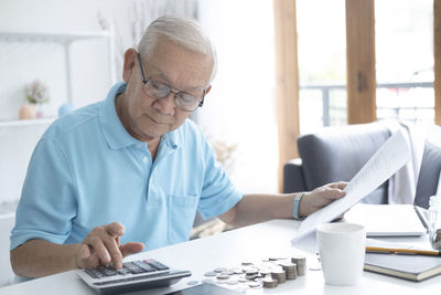 Midsection of man using mobile phone while sitting on table