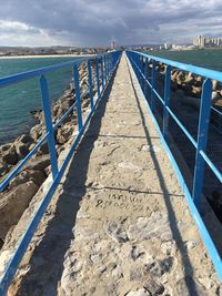 Walkway leading to sea against sky