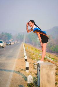 Side view of woman standing on road against sky