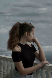 Young woman standing by sea against sky