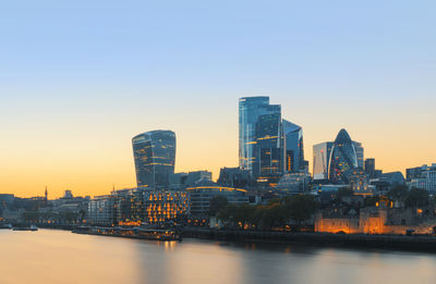 River and buildings against clear sky during sunset