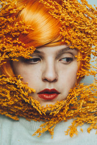 Close-up of young woman looking away by leaves