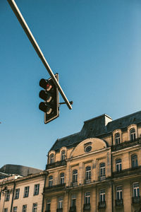 Low angle view of stoplight in city against clear blue sky