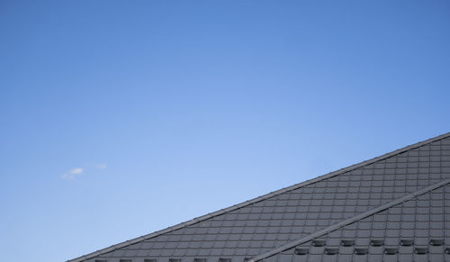 Low angle view of building roof against clear blue sky