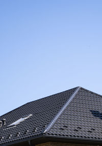 Low angle view of building roof against clear sky