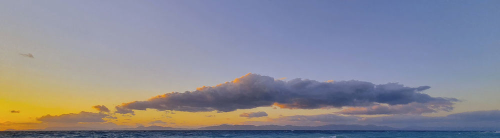 Sea horizon at sunset with clouded sky.