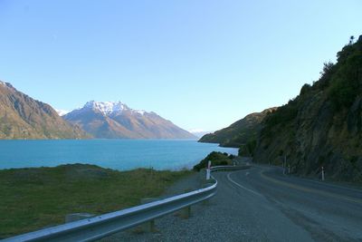 Road leading towards mountains against blue sky