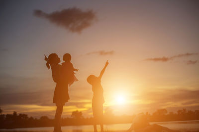 Silhouette people standing against sky during sunset