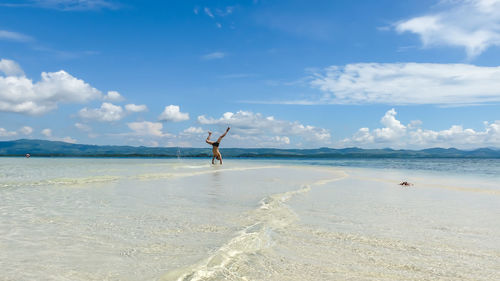 Full length of man doing handstand in sea against sky