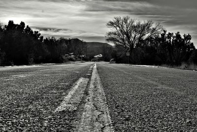 Road by trees against sky