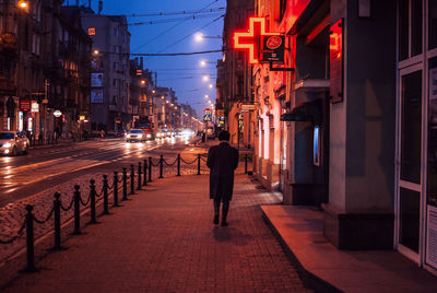 Rear view of a man walking on street at night