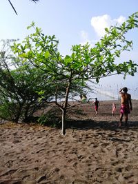 Rear view of people standing at beach against sky