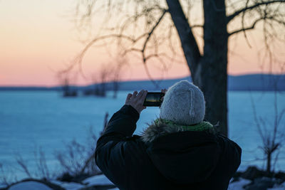 Rear view of person photographing during sunset