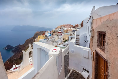 Buildings in town by sea against sky