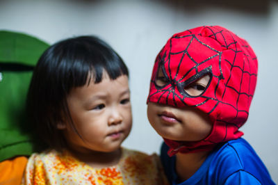 Close-up of boy in superman costume with sister at home