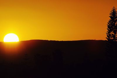 Scenic view of silhouette landscape against orange sky