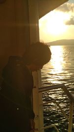 Man standing by sea against sky during sunset