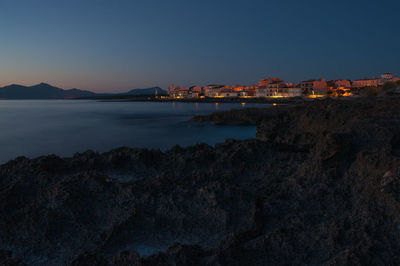 Sea by buildings against sky during sunset